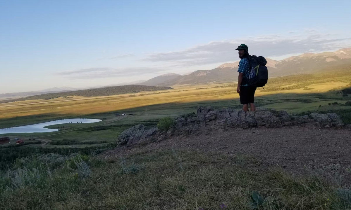 Oboz Footwear ambassador Tyler stands at an overlook during a backpacking adventure. 
