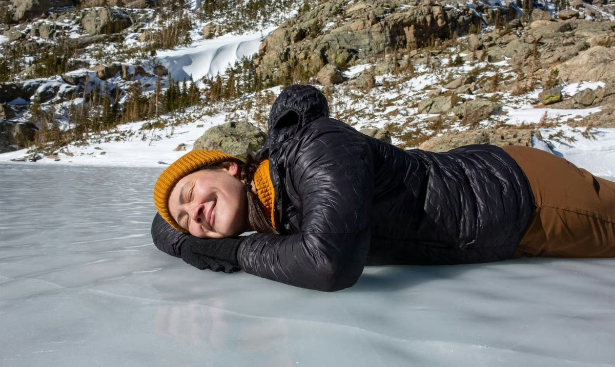 Oboz ambassador Kylie Yang lays on a frozen lake during winter hike.