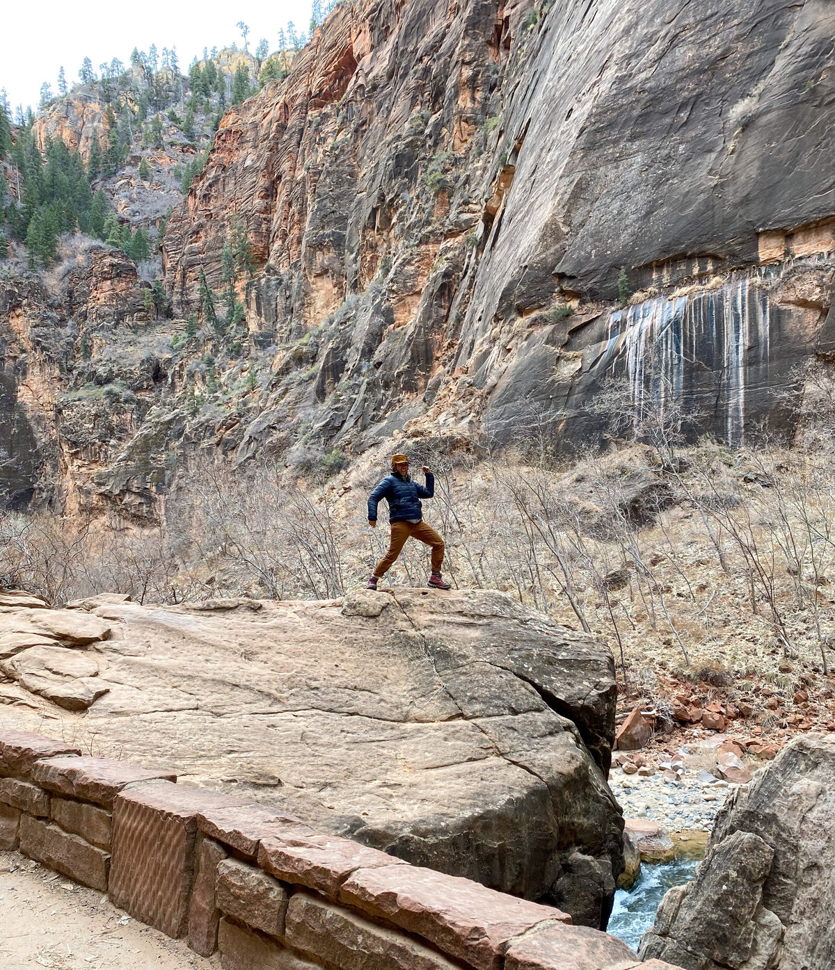 A person striking a pose on top of a boulder in the Bridger Mids Rio Red