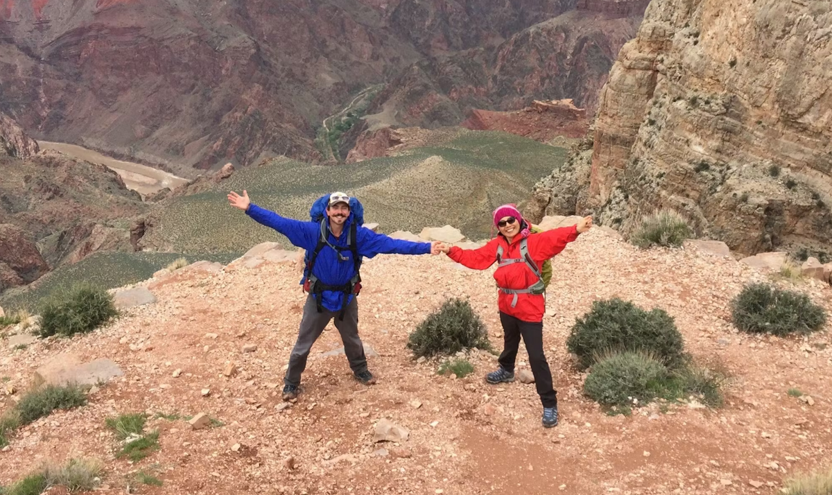 Two stoked adventurers wearing Oboz hiking boots at the top of the mountain landscape.