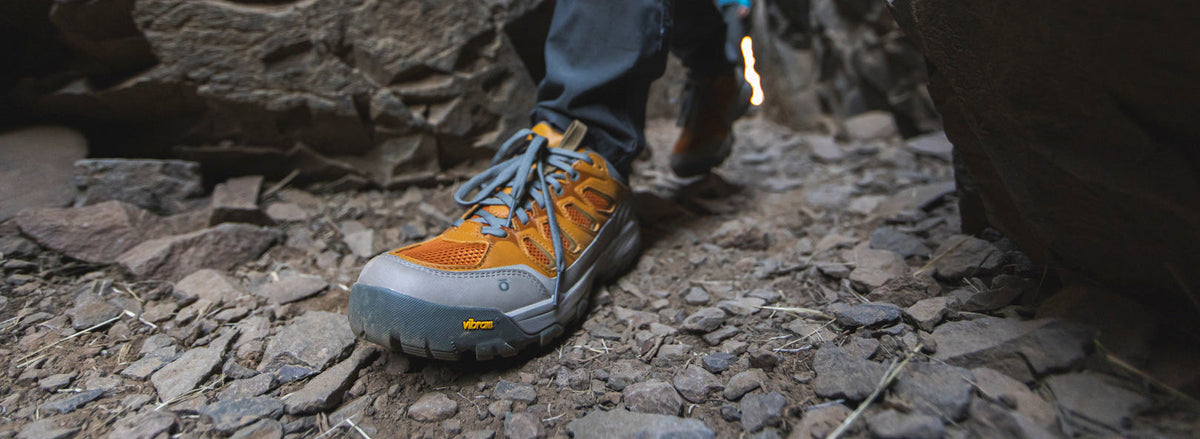 Close-up of the Oboz Sawtooth X Pro low hiking shoes on a rocky trail with a person navigating through rocks.