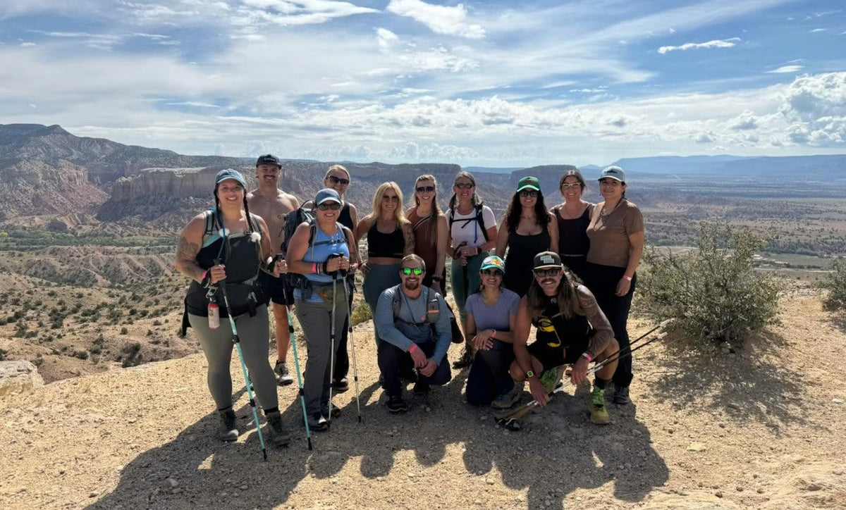 A group of hikers poses for a picture on top of a dessert mesa.