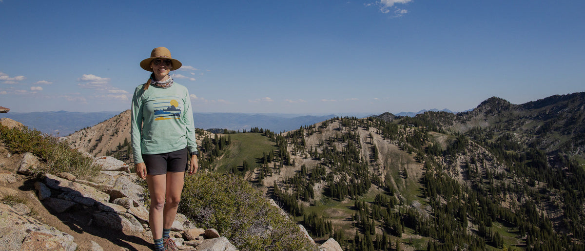 Hiker posing for a picture on the top of a mountain wearing Oboz hiking boots.