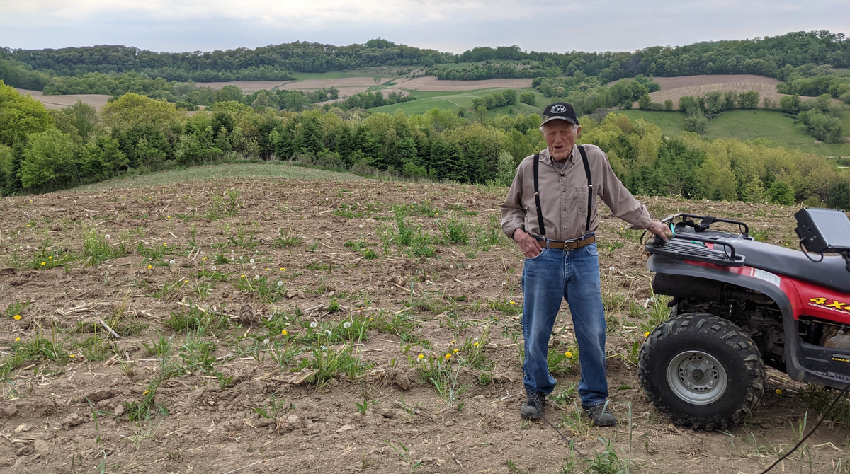 A farmer out in the field with his ATV four wheeler.