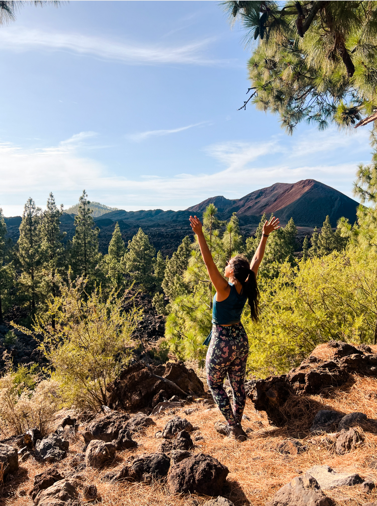 Woman on a trail soaking up the sun with her arms up in the air.