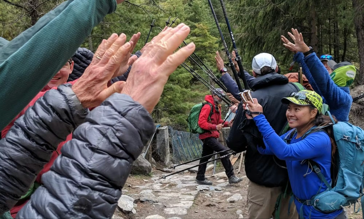 Group of hikers cheering one another on along the trail with their trekking sticks.