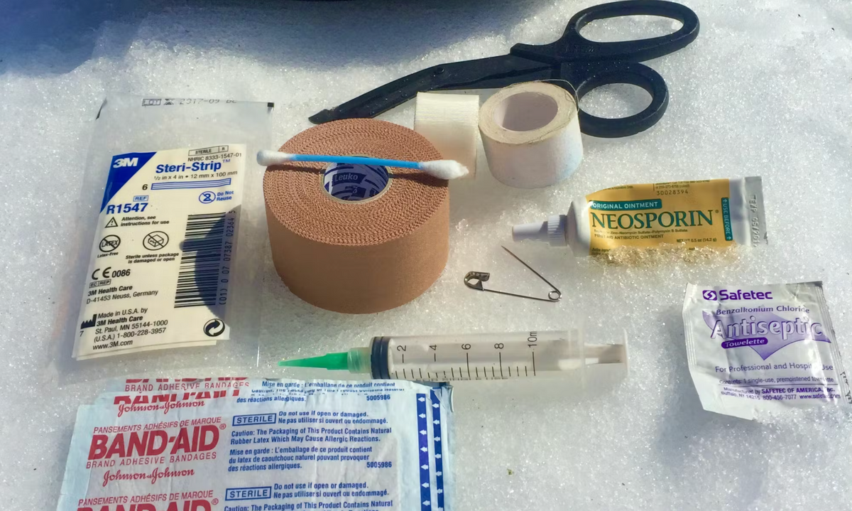 First Aid kit placed on snow to show the recommend essentials one should carry