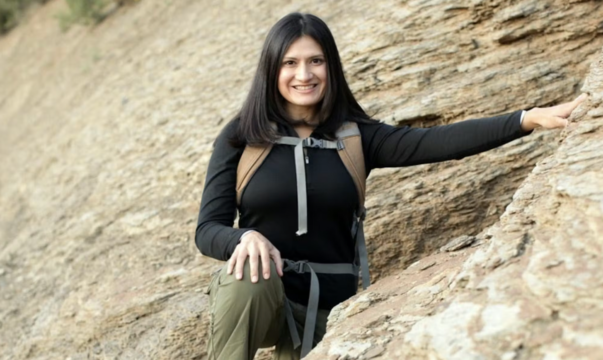 Karla Amador standing along a rock wall wearing Oboz hiking shoes
