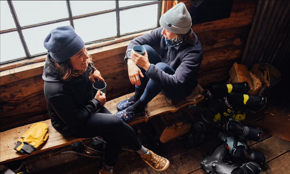 Corinne Prevot, founder of Skida enjoying a conversation in a cabin wearing Oboz Whakata Puffy slippers.