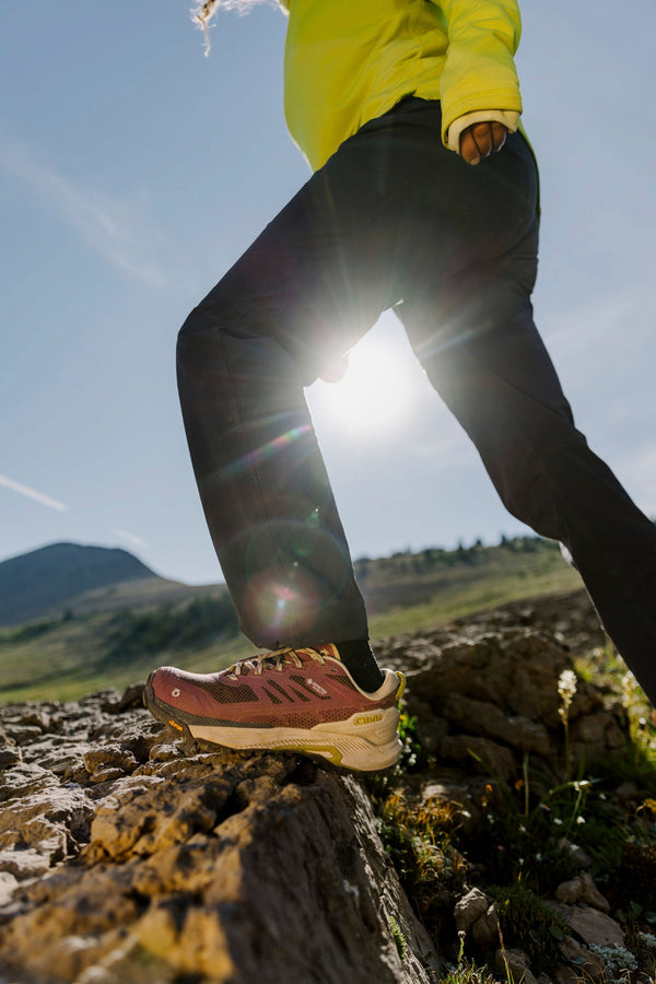 Hiker steps onto a rocky step with Oboz trail shoes