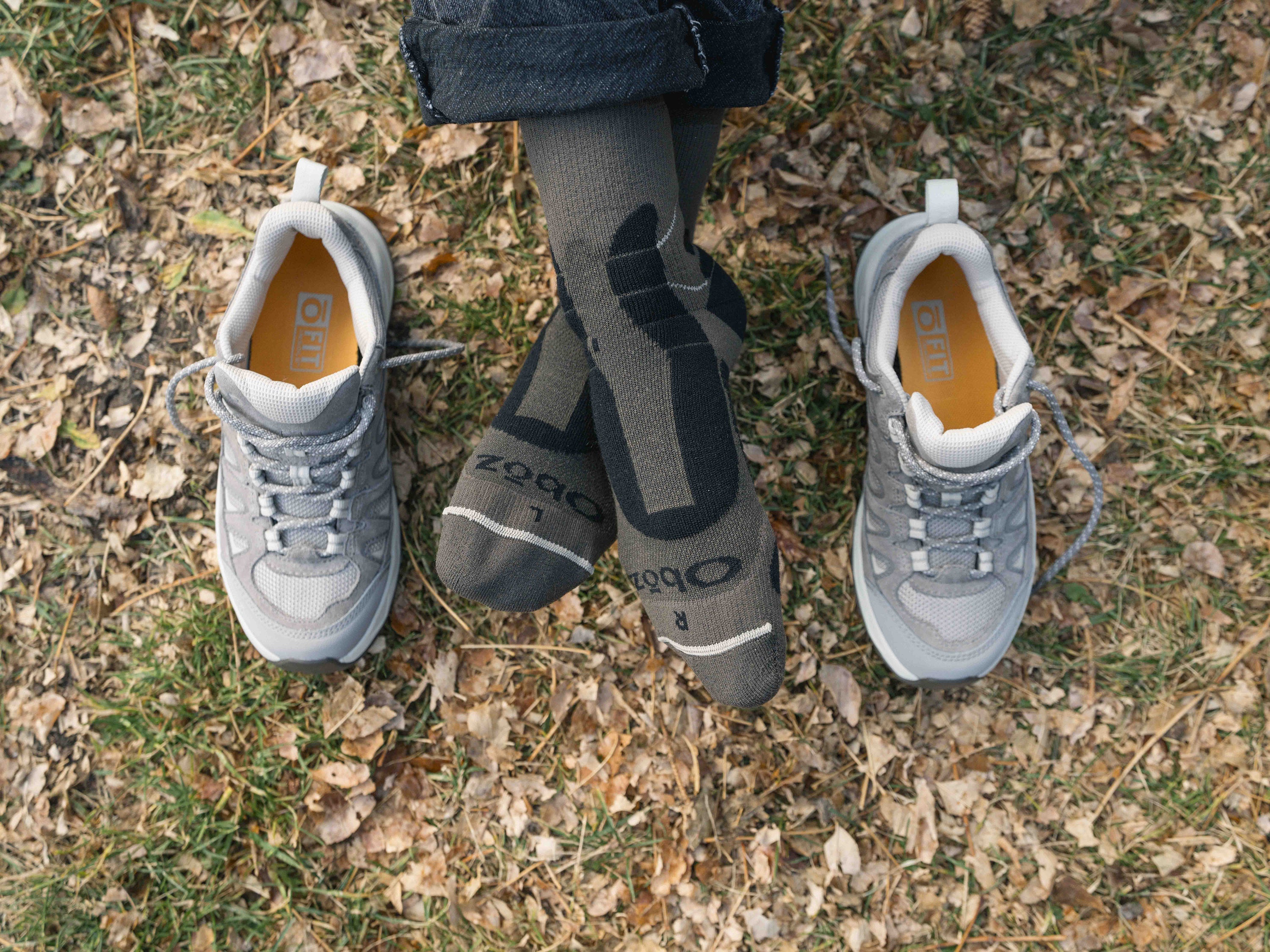 Gray Oboz Sawtooth Ascent shoes and brown Oboz rugged merino wool socks on a grassy ground