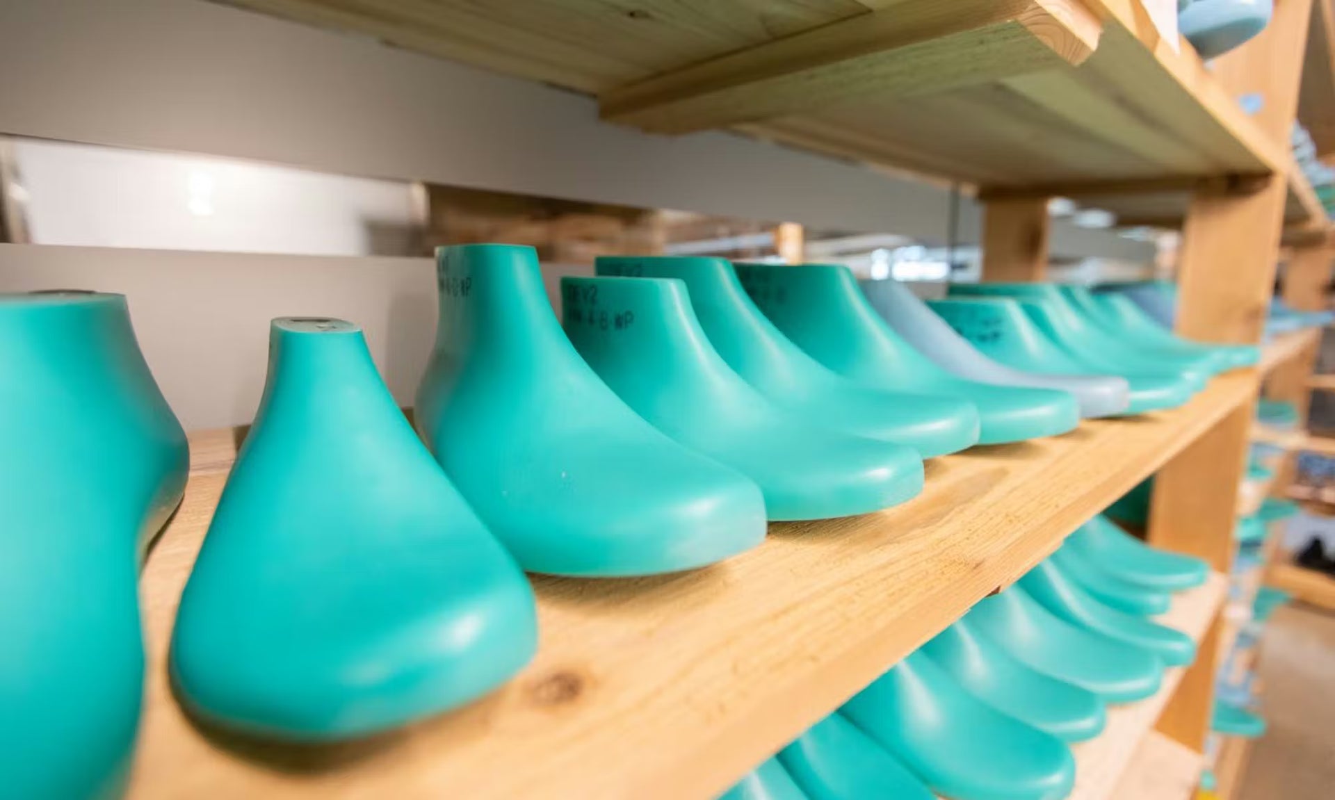 Row of footwear last molds on wooden shelves