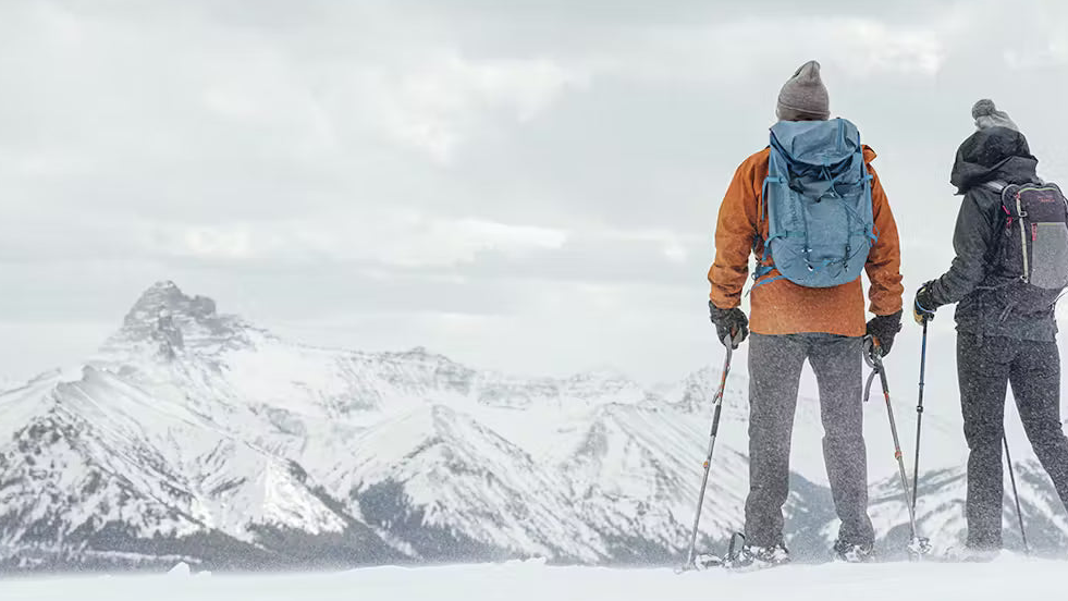 Two people snowshoeing in Oboz footwear in a mountain winter landscape.