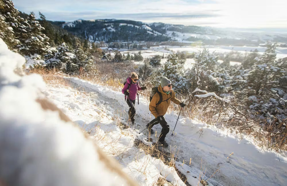 Hikers climb up a snowy mountain trail in Oboz Bangtail winter boots.