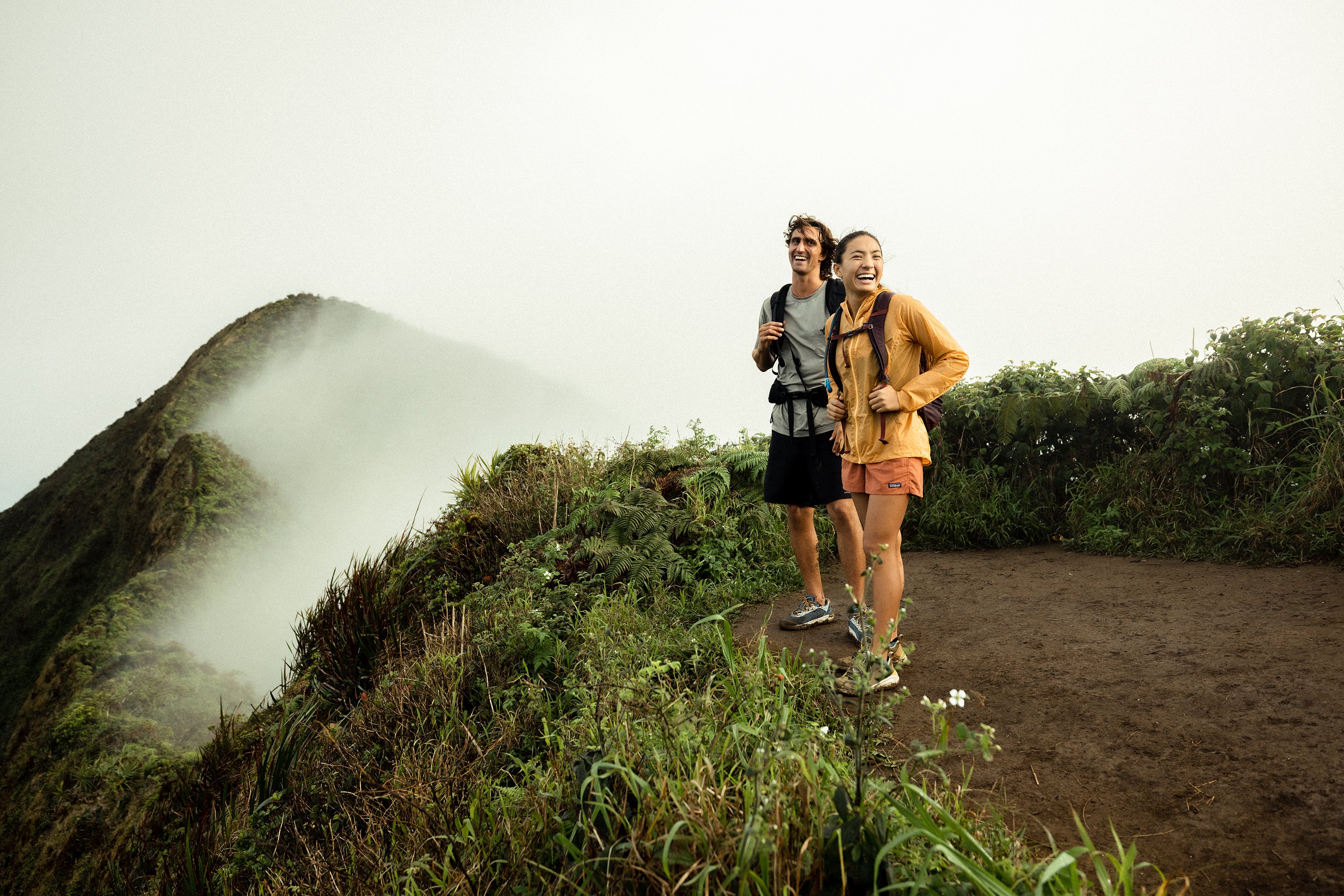 Two people hiking on a misty mountain trail in Hawaii.