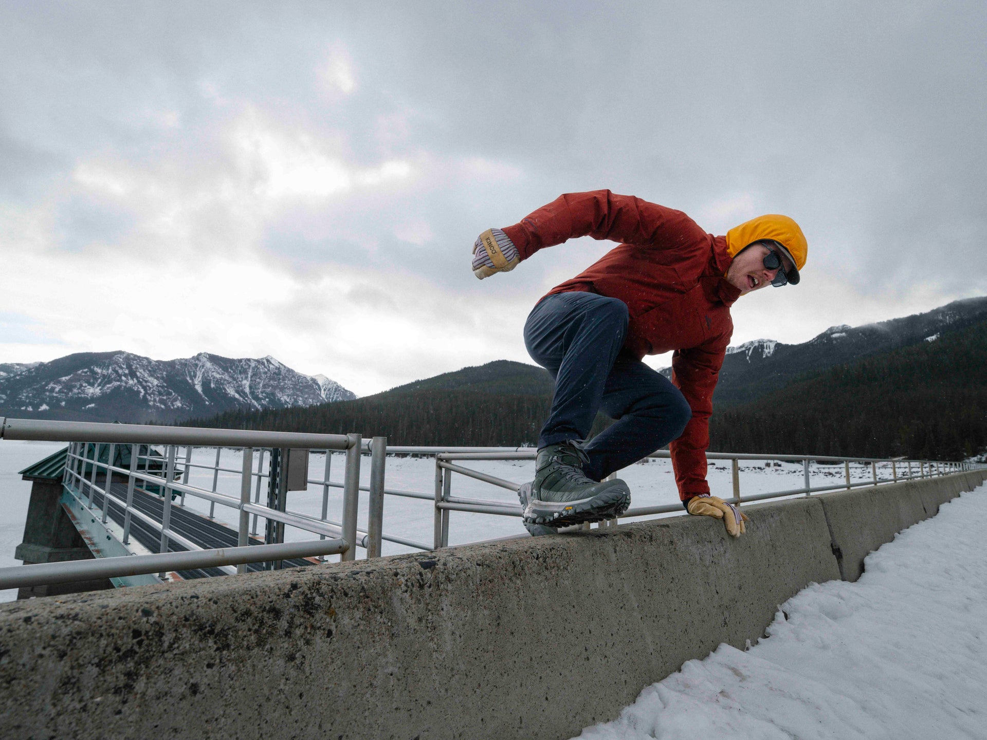 Person jumping over a concrete ledge with mountains in the background in Hyalite Canyon.
