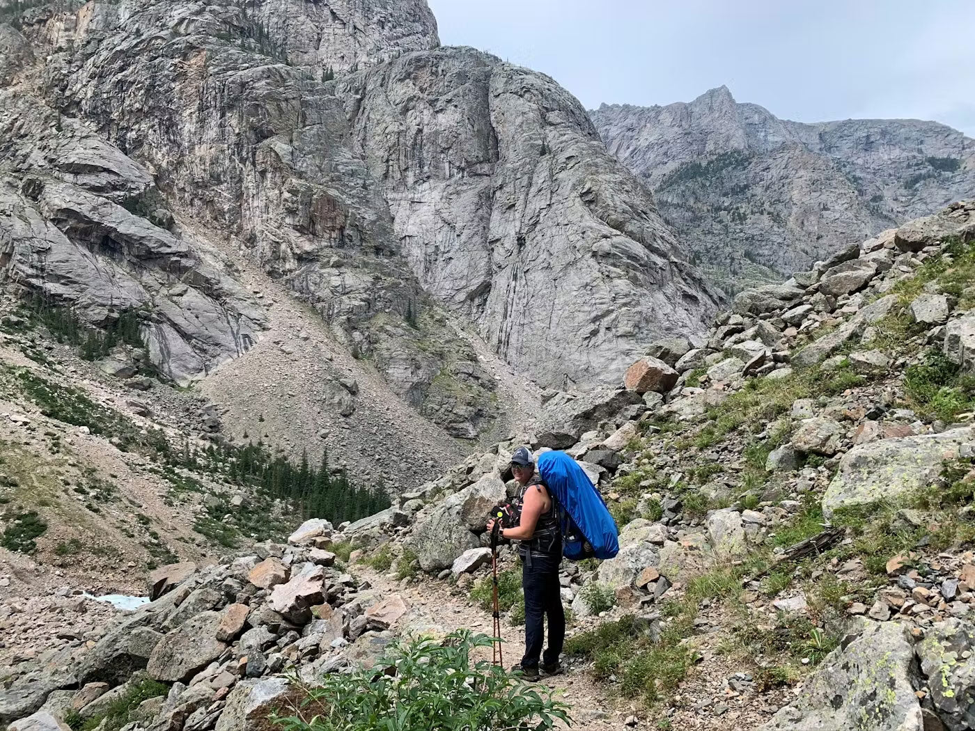 Person hiking in a mountainous area with rocky terrain and cliffs.