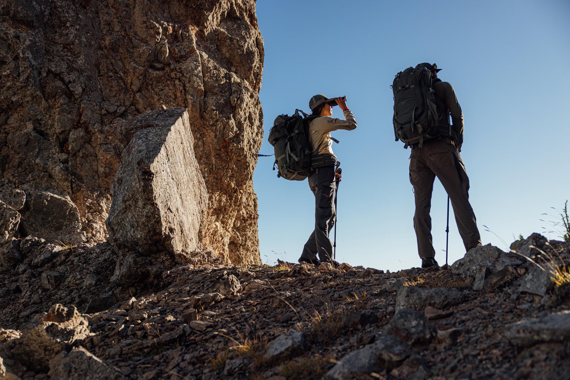 Two hikers enjoying the view from a rugged rocky ridge.