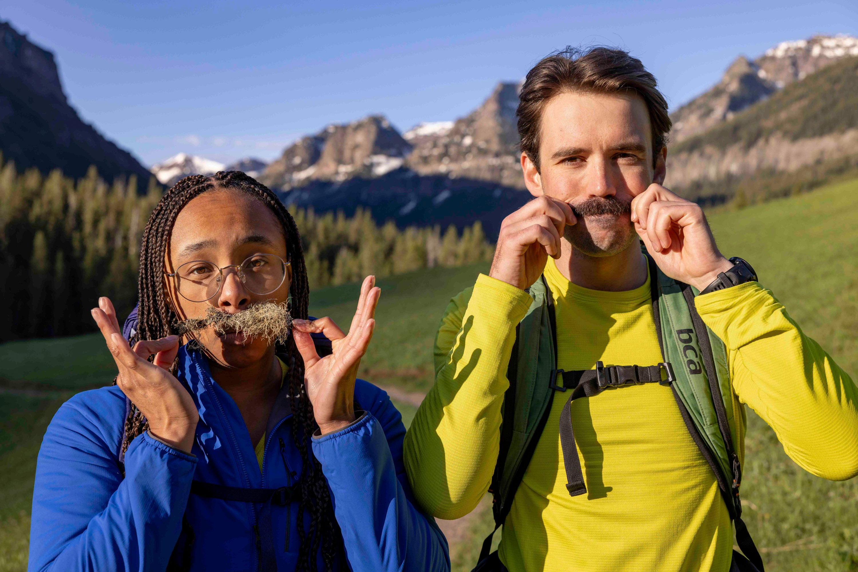Two people outdoors with mountains in the background