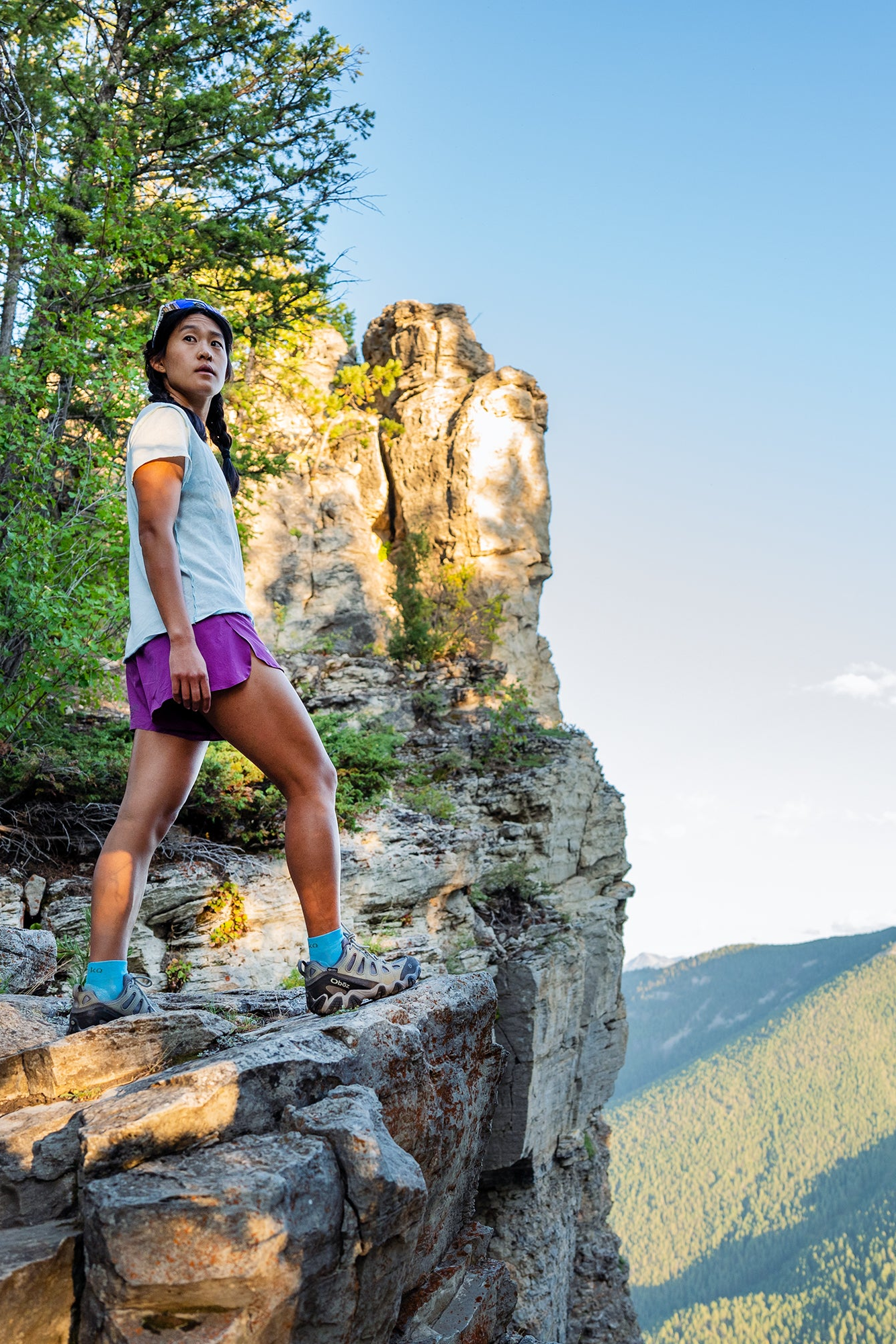 Person standing on a rocky outcrop with scenic mountain background wearing Oboz Sawtooth II hiking boots.
