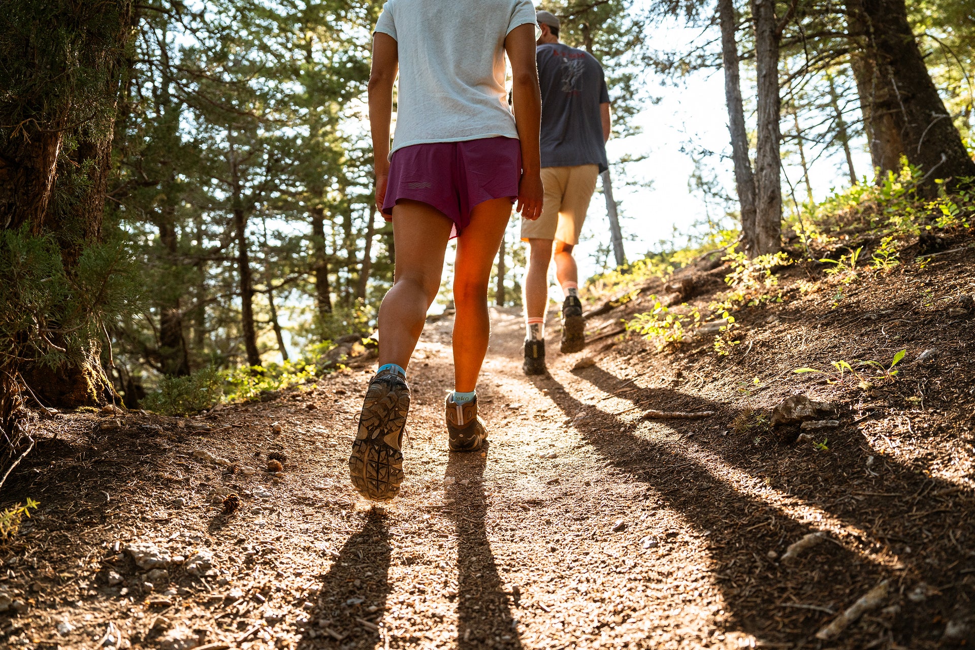 Two people hiking on a trail through a forest wearing Oboz Sawtooth II boots