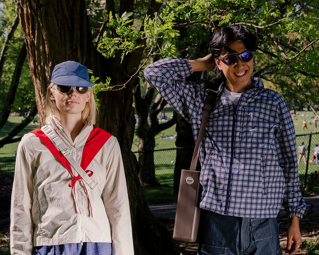 Two trendy hikers wearing sunglasses in a park.