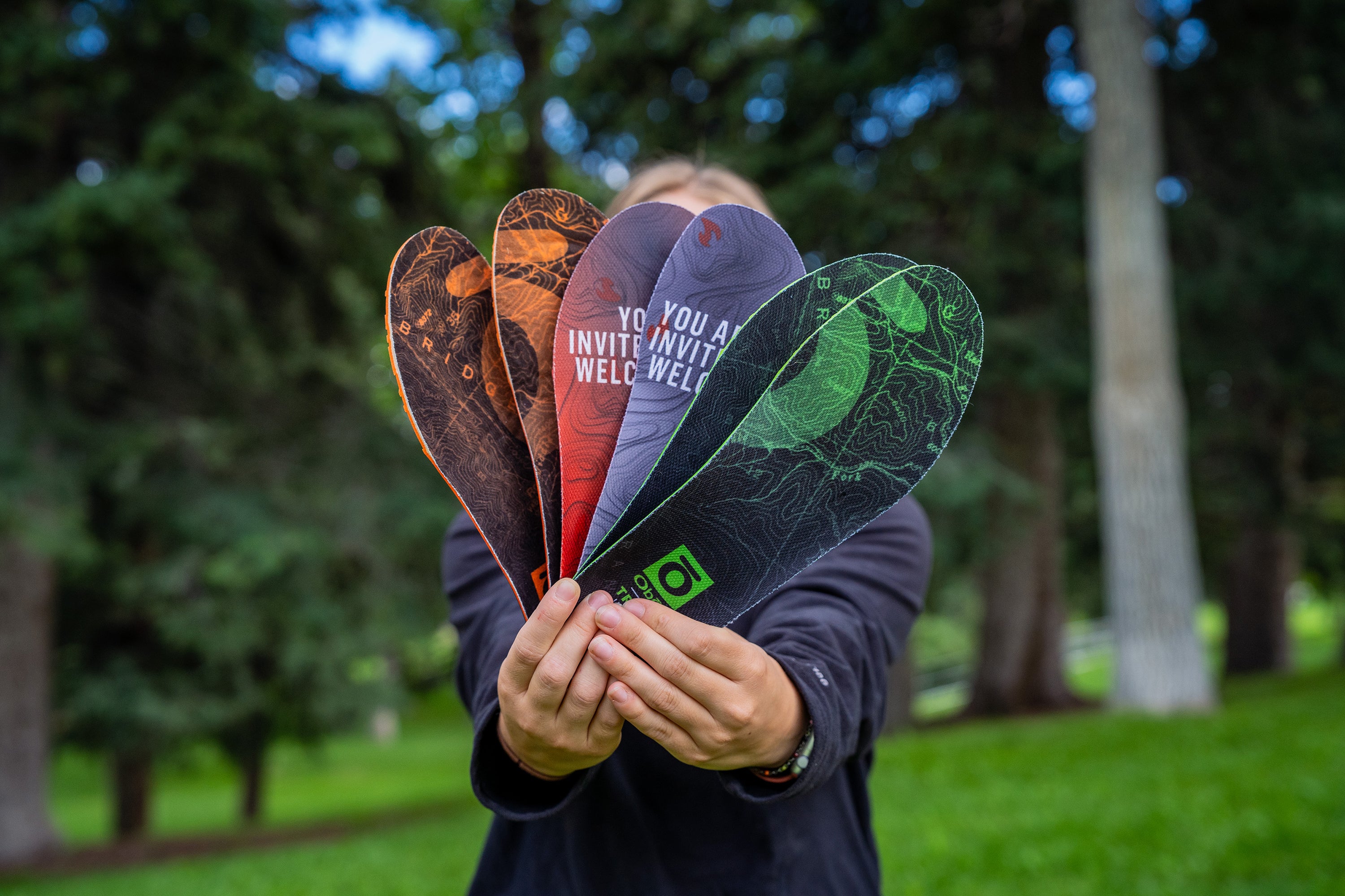 Person holding Oboz Trail insoles in a park setting