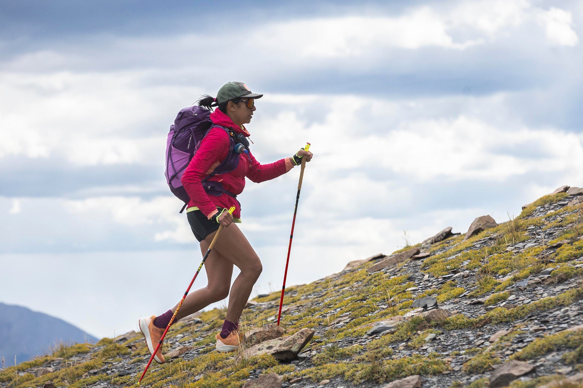 Person hiking on a mountain in Oboz Katabatic LT shoes with hiking poles and backpack