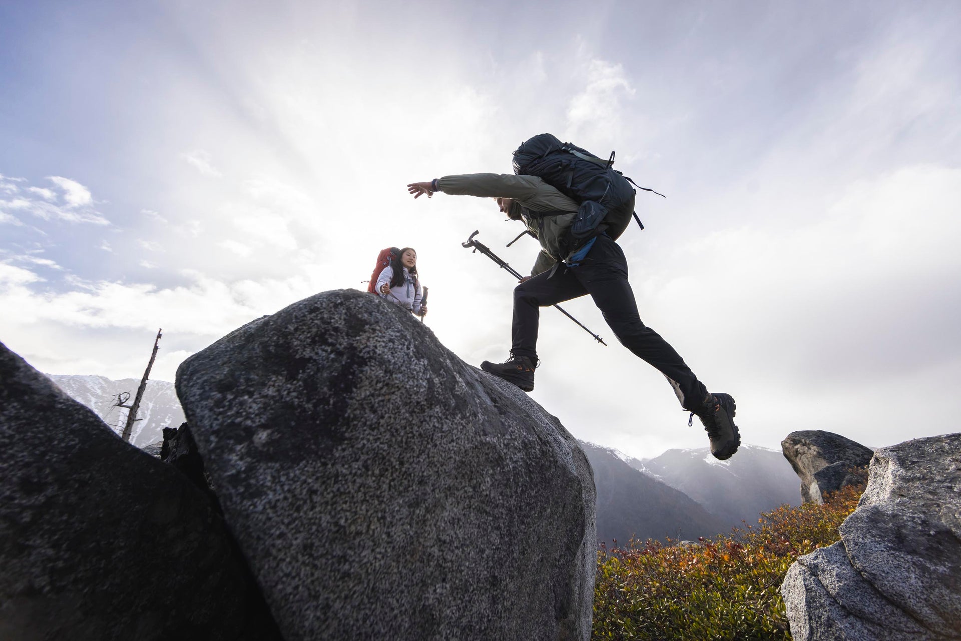 Two hikers with backpacks climbing over large rocks wearing Oboz Bridger Ridge hiking boots