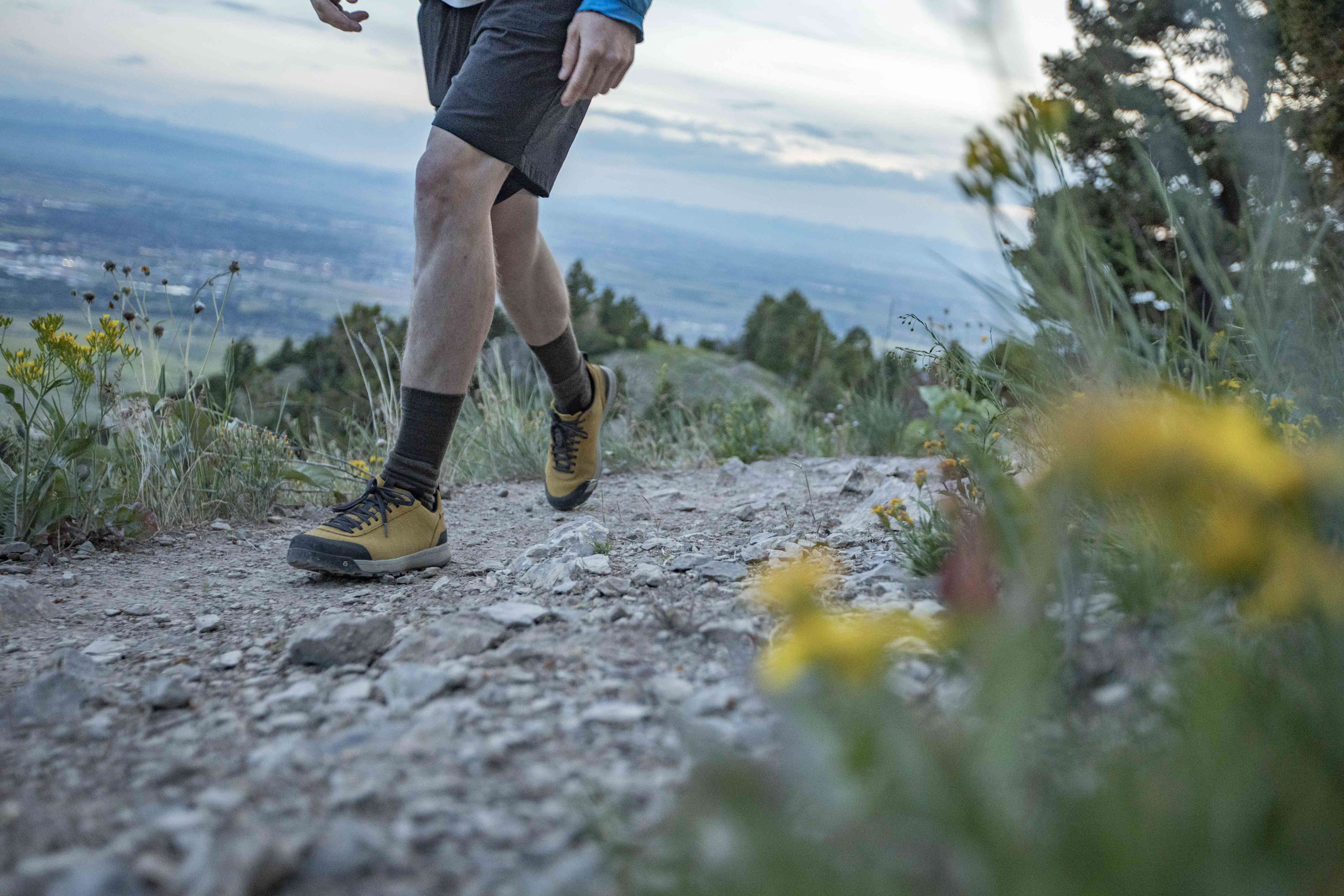 Person hiking on a trail wearing Oboz Bozeman II hiking shoes in the Sulphur yellow color.