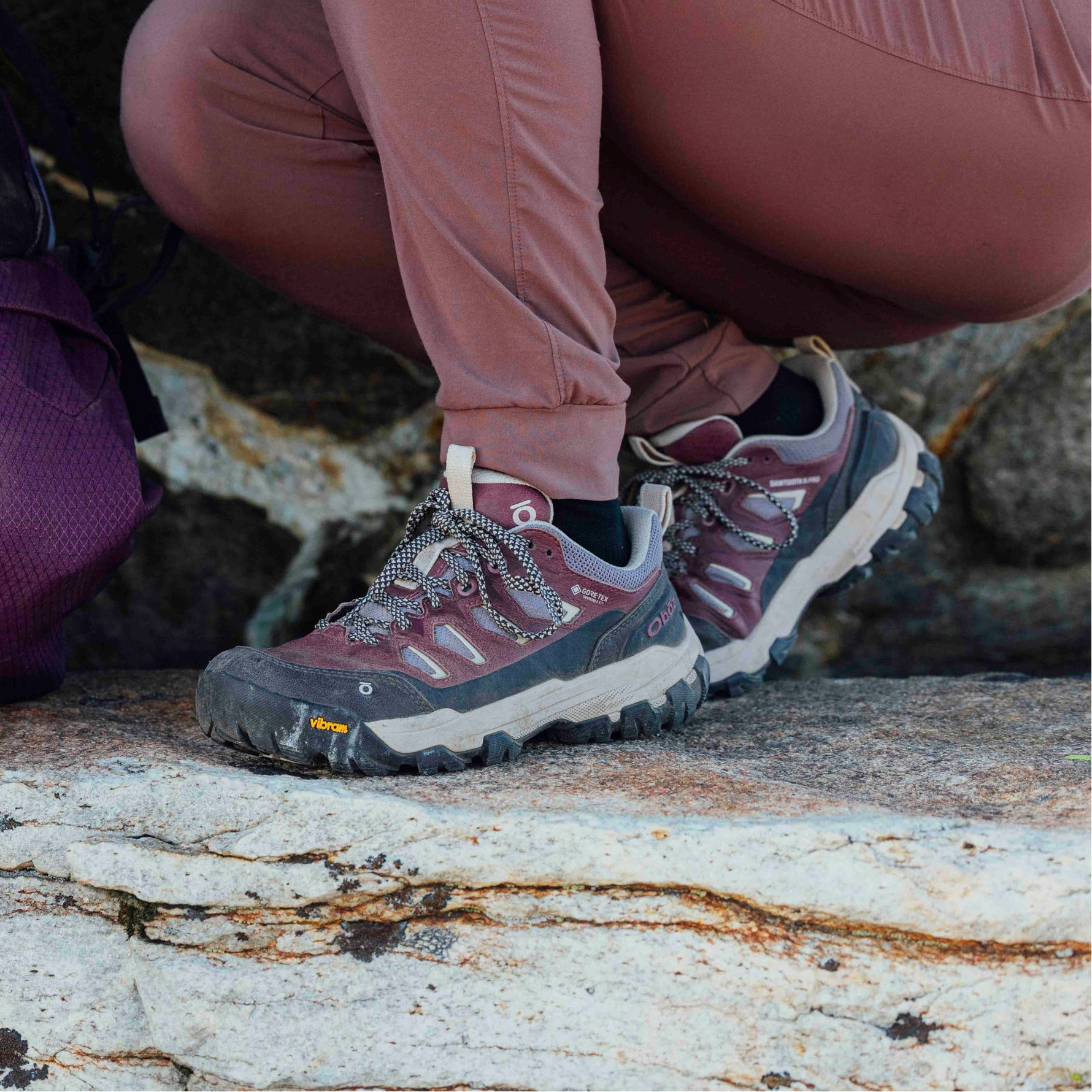 Person wearing pink hiking boots on a rocky surface
