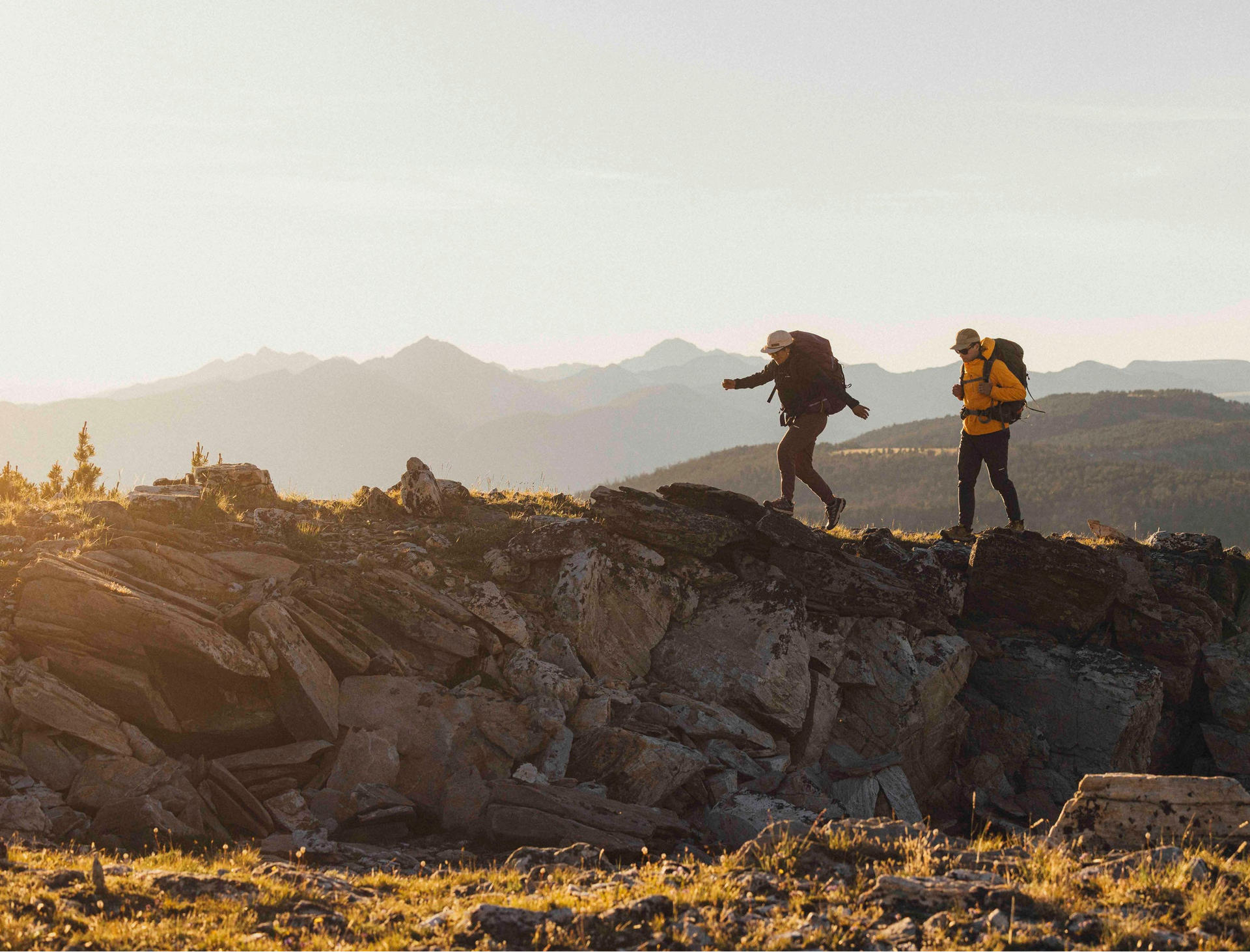 Two hikers on a rocky mountain ridge with a scenic landscape.